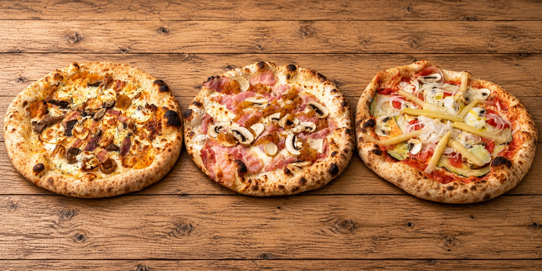 Tres pizzas artesanales sobre una mesa de madera