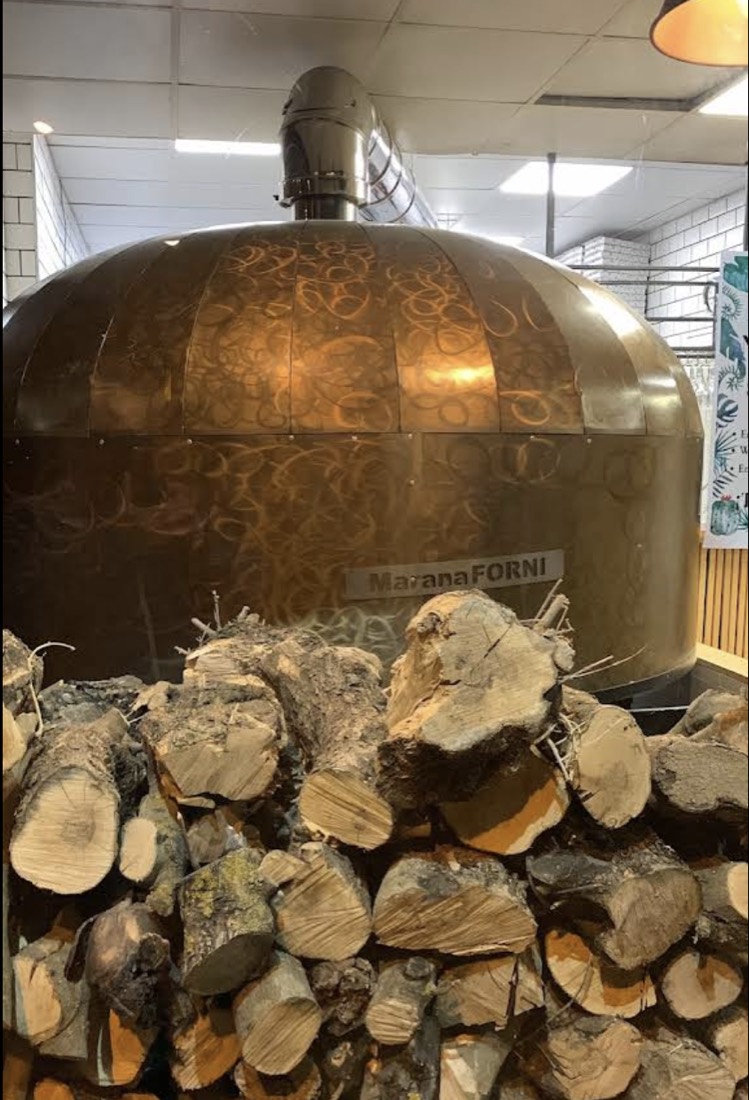 Horno de leña MamForni del Botánico con leña apilada